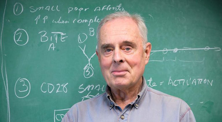 Rainer Storb in front of a blackboard
